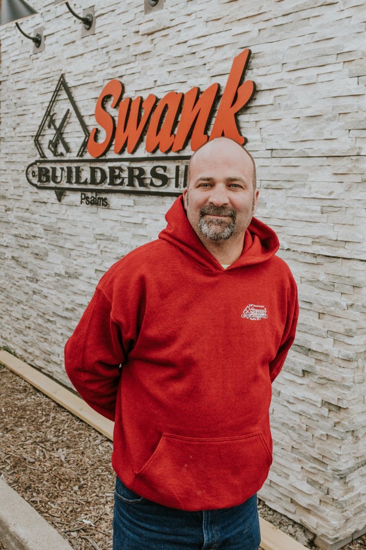Daryl Staley of Swank Builders Inc standing in front of the company sign for custom home construction services in Flint, MI.-optimized