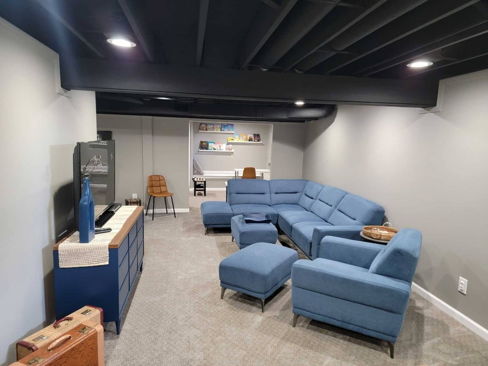 Finished basement living room with modern seating and recessed lighting by Swank Builders Inc in Flint, MI.