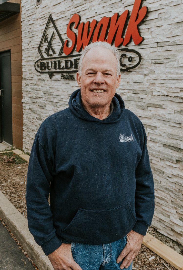 Jim Gordon of Swank Builders Inc standing in front of the company sign for custom home services in Flint, MI.-optimized