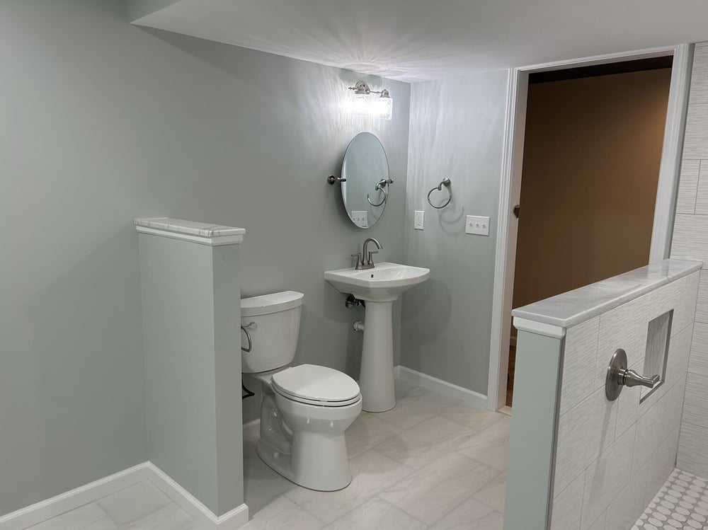 Finished basement bathroom with tile shower, pedestal sink, and modern fixtures in Goodrich MI