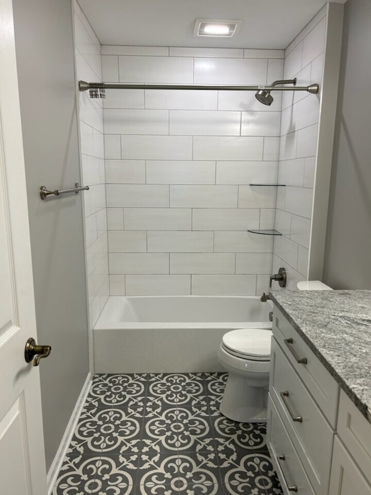 Swank Builders Inc bathroom remodel featuring tub shower combo with subway tile walls and patterned tile floor in Burton MI