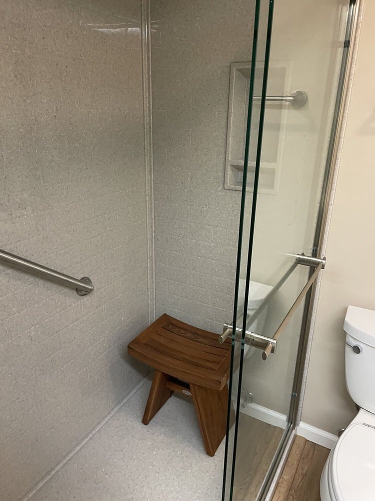 Swank Builders Inc bathroom remodel featuring walk in shower with bench seating and frameless glass door in Burton MI