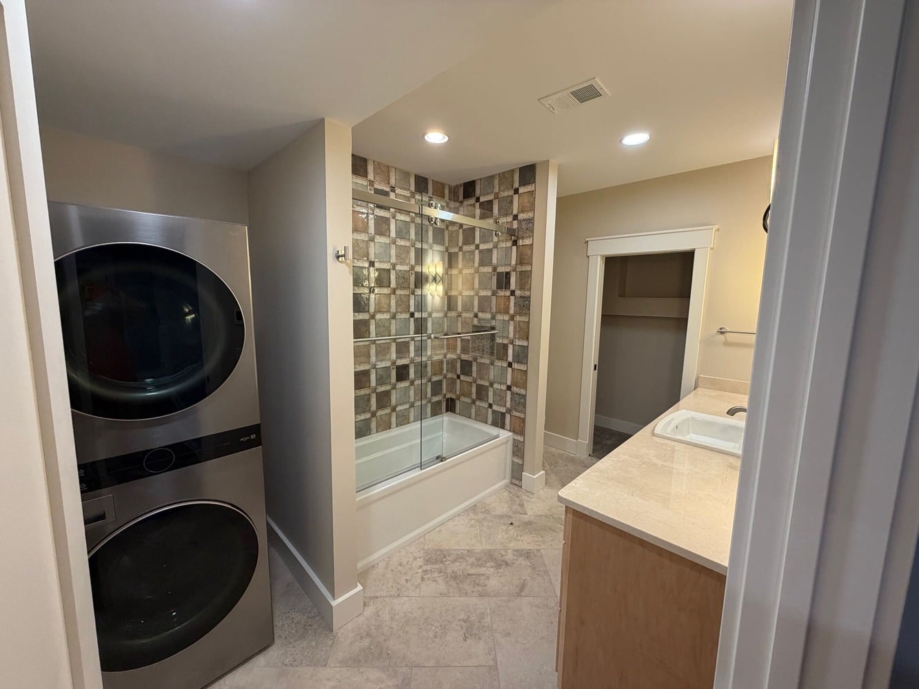 Swank Builders Inc custom bathroom and laundry combo with stacked washer dryer and tub shower in Michigan