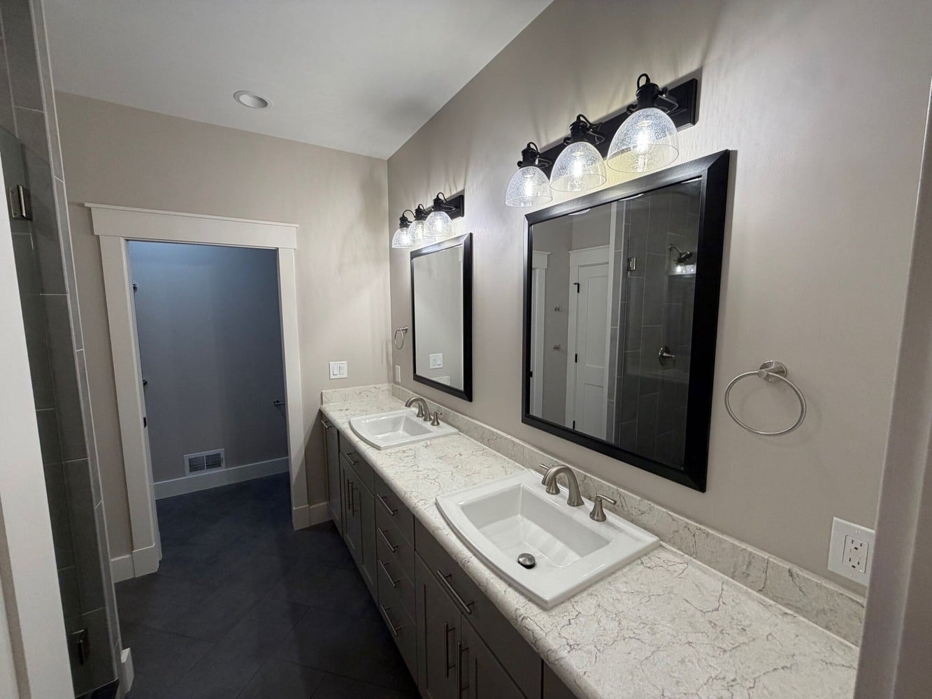 custom bathroom with dual sinks, framed mirrors, and vanity lighting in Michigan new construction