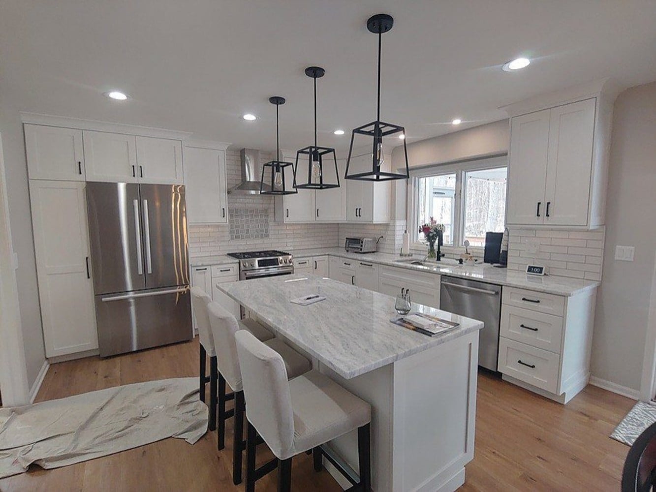 Swank Builders Inc completed this modern kitchen remodel with white cabinets, island seating, and pendant lighting in Flint, MI.