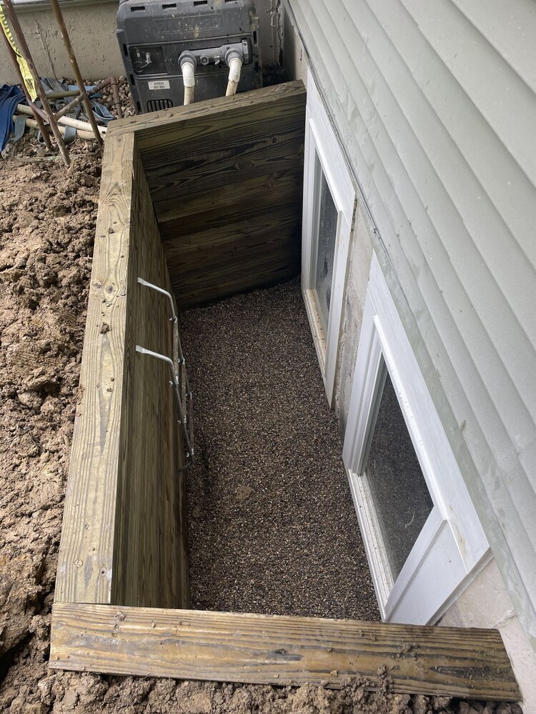Swank Builders Inc installed a basement egress window with treated wood window well and gravel drainage in Genesee County, MI.